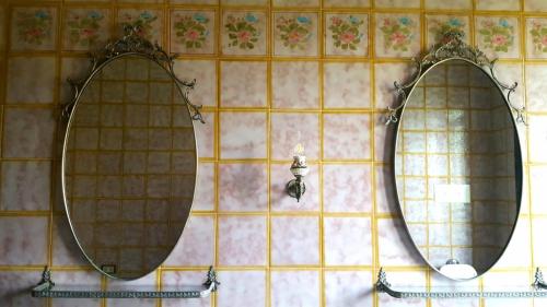 two mirrors on a tiled wall in a bathroom at Villa Giacinti in Padova