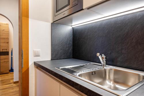 a kitchen with a sink and a black counter top at Appartement Schlern Living 1 in Völs am Schlern