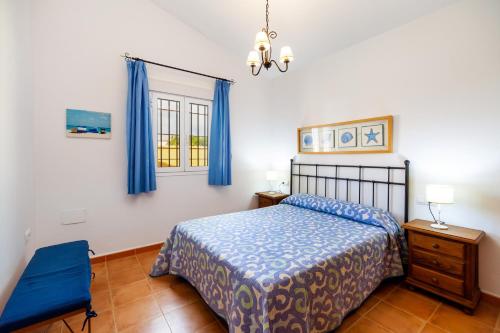 ein Schlafzimmer mit einem Bett und einem Fenster mit blauen Vorhängen in der Unterkunft Luisa 1 in Conil de la Frontera