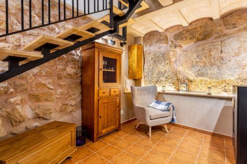 a living room with a staircase and a chair at Entre Eras Aptos Rurales La Bodega in Ademuz