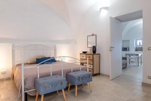 a bedroom with a bed with two blue stools at Arco Antelmy in Ceglie Messapica