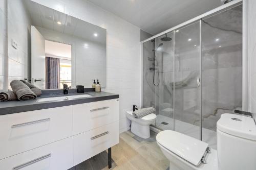 a white bathroom with a shower and a toilet at Calafenga in Calafell
