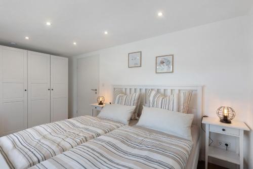 a white bedroom with a large bed with striped sheets at Fewo Feldmann Auf Der Mauer in Schmallenberg