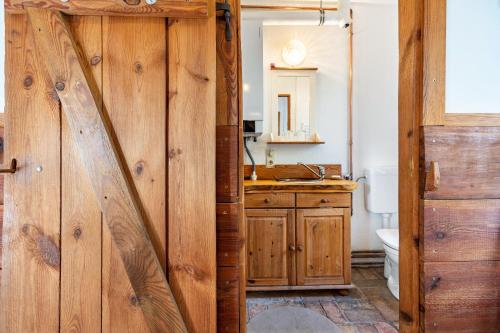 a bathroom with a wooden door with a sink and a toilet at Casa del Sol - Fachwerkhäuschen in Lychen