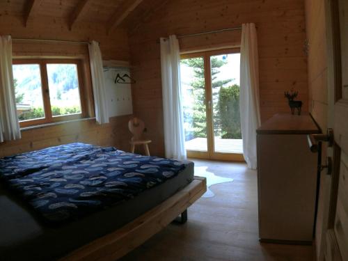 a bedroom with a bed and two windows at Chalet Finkennest in Neukirchen am Großvenediger