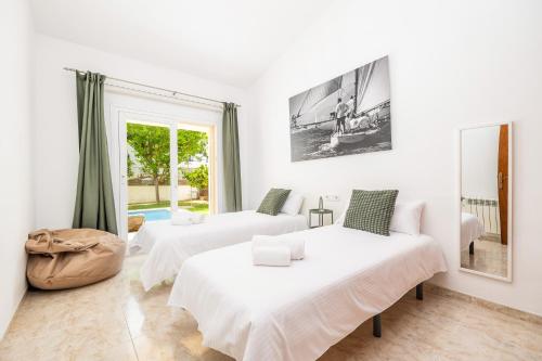a white room with two beds and a window at Villa Ramón in Palma de Mallorca