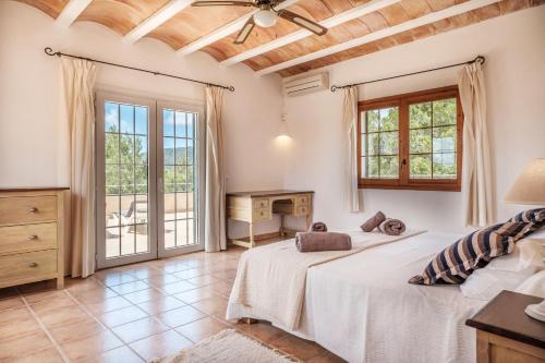 a bedroom with a bed and a desk and windows at Can Moustique in Sant Josep de sa Talaia
