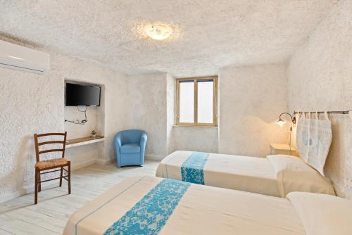 a bedroom with two beds and a chair and a tv at Casa Rocca in Bosa