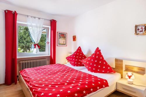 a bedroom with a bed with red pillows and a window at Ferienwohnung Schwarzwaldhirsch in Unterkirnach