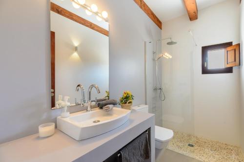 a white bathroom with a sink and a toilet at Casa S'Olibassa in La Mola
