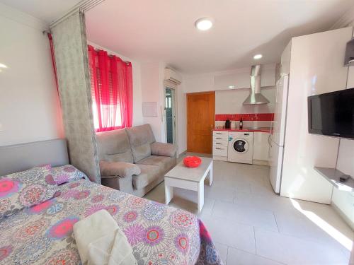 a bedroom with a bed and a couch and a kitchen at Estudio lola in Nerja