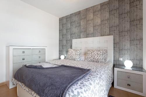 a bedroom with a bed and a stone wall at Casa Mar y Luz in Morro del Jable