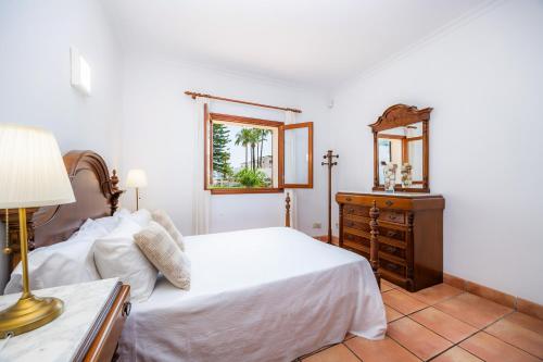 a bedroom with a bed and a dresser and a mirror at Dofí in Cala Millor