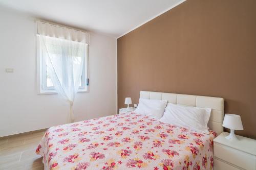 a bedroom with a bed with a floral bedspread and a window at Villa Ohana in Syracuse