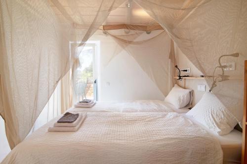 a bedroom with a white bed with a window at Casa Frango in Moncarapacho