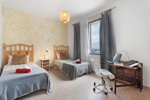 a bedroom with two beds and a desk with a computer at House in Anaga in Almáciga