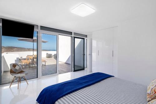 a bedroom with a bed and a balcony with a table at Tritón 6 in La Santa