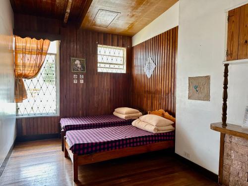 a bedroom with two beds in a room with wooden walls at Baguio BELL Staycation in Baguio