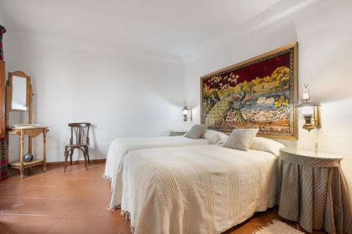 a bedroom with two beds and a painting on the wall at Casa de la Fuente in Bubión