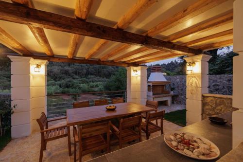 an outdoor dining area with a wooden table and chairs at Villa Logas Hill in Peroulades