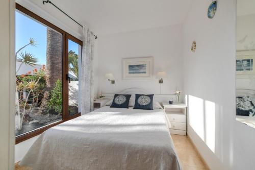 a bedroom with a bed and a large window at Bungalow Playa Bastián in Costa Teguise