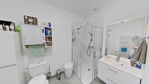 a white bathroom with a shower and a toilet at La maison de Fabien - Piscine in La Tranche-sur-Mer