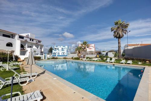 a large swimming pool with chairs and palm trees at Victoria's House in Sagres