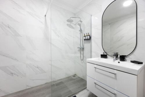 a white bathroom with a shower and a mirror at Victoria's House in Sagres