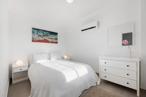 a white bedroom with a bed and two night stands at Victoria's House in Sagres