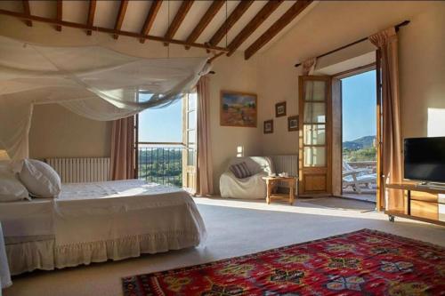 a bedroom with a bed with a television and a balcony at Sa Mesquida de D’alt in Capdepera