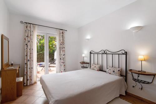 a bedroom with a white bed and a balcony at Apartamento Tavirasol in Tavira