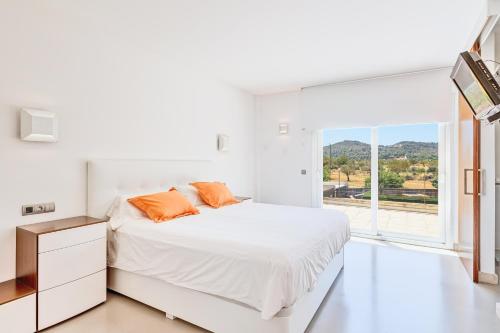 a white bedroom with a bed and a large window at Villa Ronda Estación in Porreres