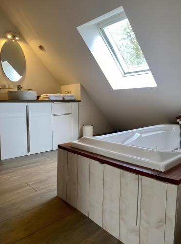 a bathroom with a large bath tub and a skylight at Gîte De La Ferme Du Tilleul in La Pellerine