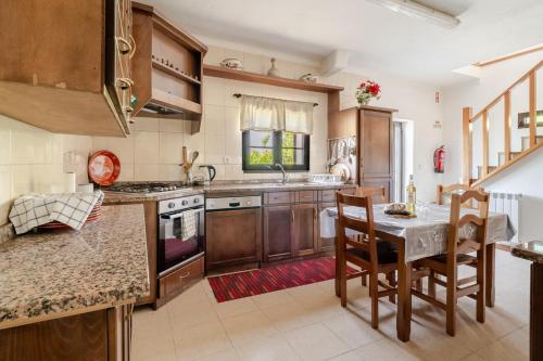 a kitchen with wooden cabinets and a table and chairs at Casa Mourelo Alojamento Local in Ponte da Barca