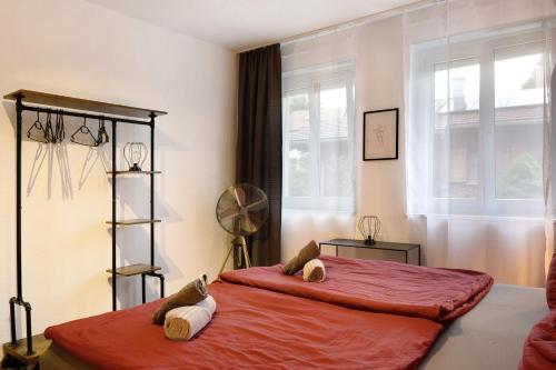 a bedroom with a large red bed with two stuffed animals on it at Amselnest in Kempten