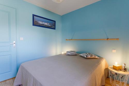 a blue bedroom with a bed with two pillows on it at La Mouette St Philibert 3 étoiles in Saint-Philibert