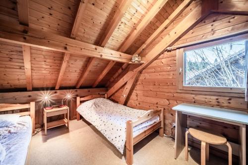 a log cabin bedroom with a bed and a desk at Chalet 6p - Le casse noisette in Verchaix