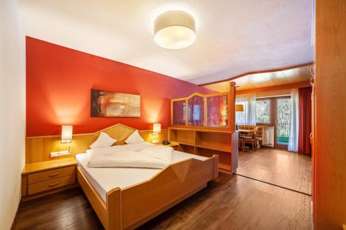 a bedroom with a large bed with an orange wall at Alpenhof Lodge Almrose in Saltusio