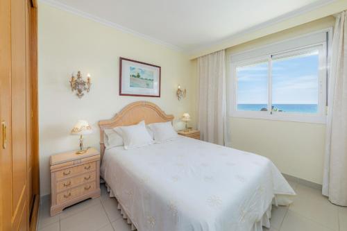 a bedroom with a bed and a window with the ocean at Frente al mar in Cala Millor