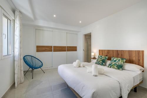 a white bedroom with a large bed and a blue chair at Alojamiento Privilegio de Alcalá in Alcalá la Real