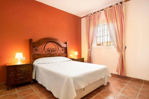 a bedroom with a bed with an orange wall at Casa Juana Zahora in Zahora