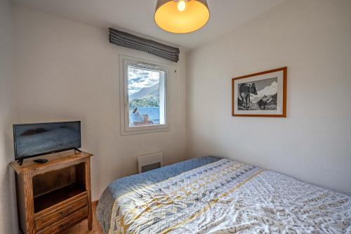 a bedroom with a bed and a tv and a window at Le calme de Ax in Ax-les-Thermes