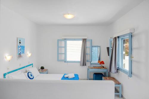 a white bedroom with a bed and windows at Pico Bello Patmos 28 in Patmos