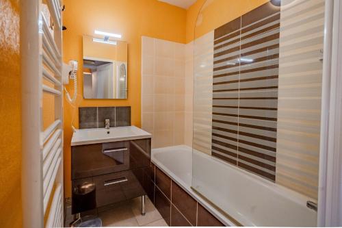 a bathroom with a tub and a sink and a bath tubermottermott at Le calme de Ax in Ax-les-Thermes