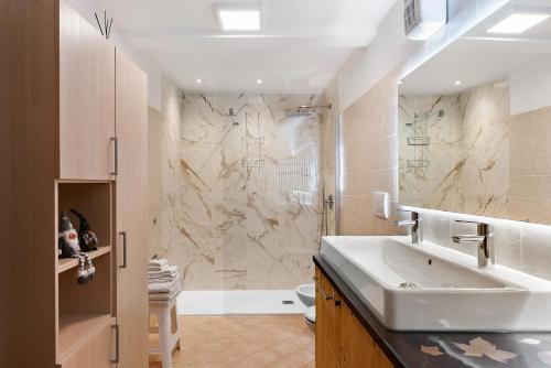 a bathroom with a sink and a marble wall at Appartamento Lory in Cavedago