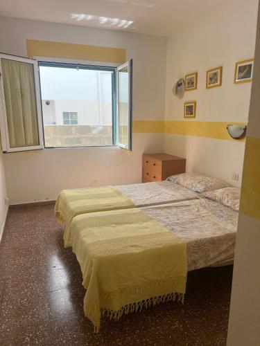 two beds in a room with a window at Una casa sulla spiaggia in Es Grau