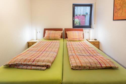 two beds in a bedroom with green sheets and pillows at Ferienwohnung Lago in Konstanz