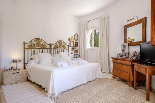 a white bedroom with a large bed and a television at Can Bernat in Can Furnet
