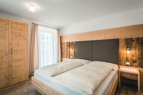 a bedroom with a large bed with a wooden headboard at Chalet La Flüta Margherita in La Valle