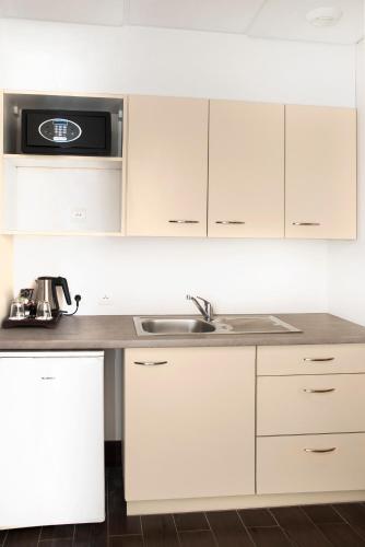 a kitchen with white cabinets and a sink at Best Western Plus Hôtel Colbert in Châteauroux